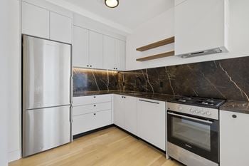 White kitchen with marble backsplash and stainless appliances
